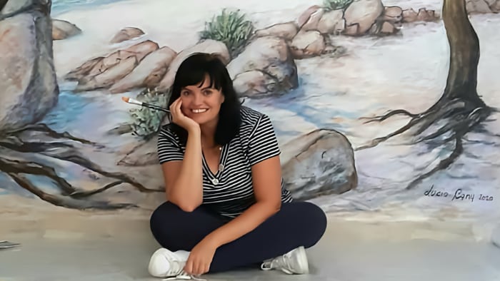 Lucia seduta di fronte ad una scena marina dipinta su un muro